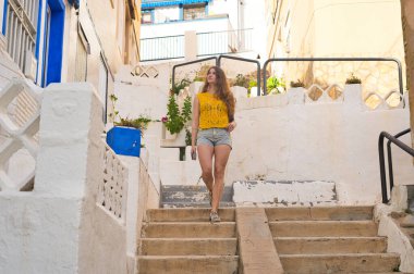 Güneşli bir yaz gününde tipik bir Endülüs beyaz köyünün merdivenlerinden inen genç bir kadın Güney İspanya 'da tatilinin tadını çıkarıyor.