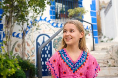 Neşeli bir çocuk canlı geleneksel bir elbise giyiyor, dekoratif bir geçmişi var, mutluluk saçıyor.