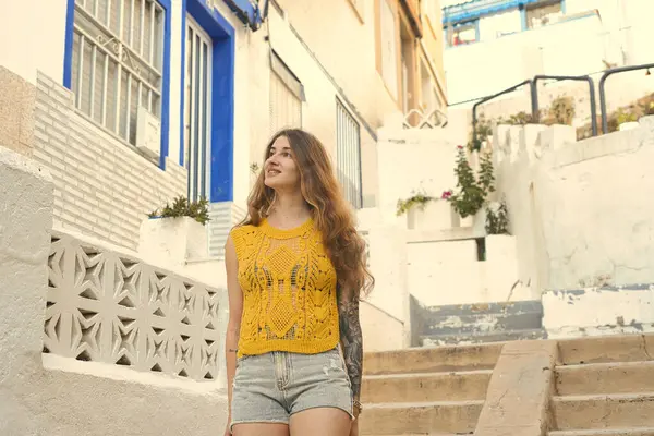 Yaz tatilinin tadını çıkaran bir turist, İspanyol kasabasının büyüleyici sokaklarını keşfediyor. Geleneksel beyazlatılmış binalara ve renkli detaylara hayran kalıyor.