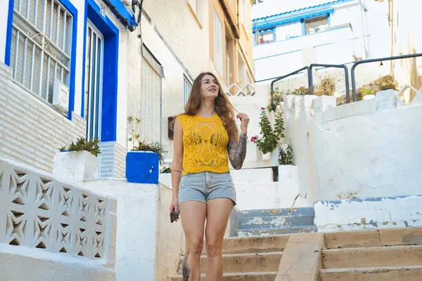 Neşeli genç bir kadın, parlak renklerle dolu canlı bir şehir ortamının basamaklarında güven içinde duruyor.