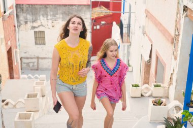 İki kadın yaz kıyafetleri içinde canlı ve renkli bir kıyı kasabasında keyifli bir gezinti yapıyorlar.