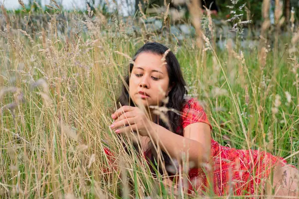 Kırmızı elbiseli bir kadının uzun otların arasında çekildiği huzurlu bir an doğayla olan bağlantısını yansıtıyor..