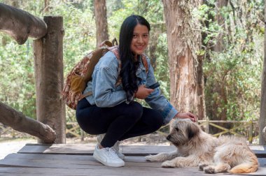 Genç bir kadın, sakin ve güzel bir orman ortamında dost canlısı köpeğiyle vakit geçirmekten gerçekten zevk alır.