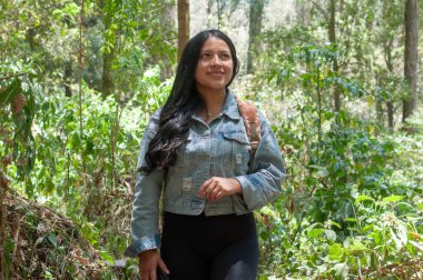 Neşeli genç bir kadın neşeyle canlı bir ormanı keşfediyor, doğanın nefes kesici harikalarını güzel bir şekilde sergiliyor.