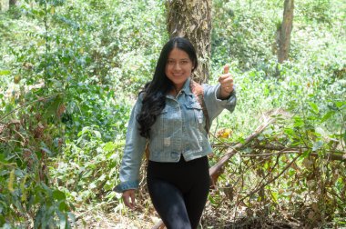 Neşeli genç bir kadın nefes kesici bir orman manzarasında heyecan verici macerasından zevk alıyor.