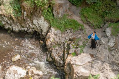 Huzurlu bir an yakalanıyor. Kayalık araziyle çevrili çarpıcı bir derenin yanında huzur içinde duran bir insan.