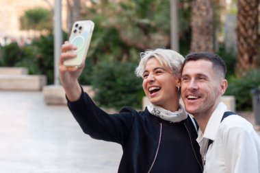 İki mutlu arkadaş açık havada eğlenceli bir selfie çekiyor, neşe ve dostluklarını sergiliyorlar.