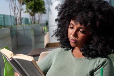 Güzel saçlı genç bir kadın, parlak ve huzurlu bir yerde ilginç bir kitap okumaktan zevk alıyor.