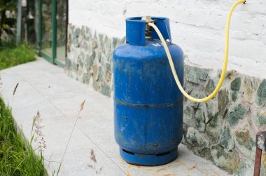 Büyüleyici bir taştan duvarın dışına dikkatlice yerleştirilmiş mavi bir gaz silindiri enerji ve kullanım gücünü temsil ediyor.