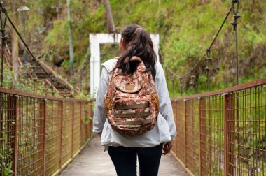 Tek başına bir gezgin asma köprüden geçer, güzelliği ve macerayı bir sırt çantasıyla kucaklar.