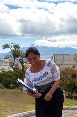 Renkli, geleneksel giysiler içinde gülümseyen yerli bir kadın dışarıdaki güzel manzaranın tadını çıkarıyor ve takdir ediyor.