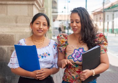 İki kadın canlı, renkli, geleneksel giysiler giyiyorlar ve dışarıda konuşmaktan mutluluk duyuyorlar.