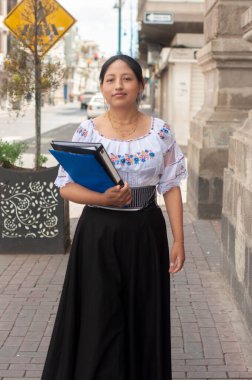 Geleneksel kıyafetler giyen bir kadın, kültürel mirası somutlaştıran bir şehir caddesinde güven içinde yürüyor..