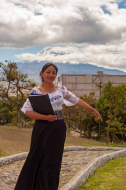 Geleneksel giysiler giymiş bir kadın, Ekvador 'da çarpıcı bir dağ manzarasını güzel bir şekilde gözler önüne seriyor.