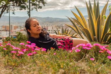 Bir kadın hayat dolu ve renkli çiçeklerle çevrili huzurlu bir anın tadını çıkarıyor, güzelliği ön plana çıkarıyor.