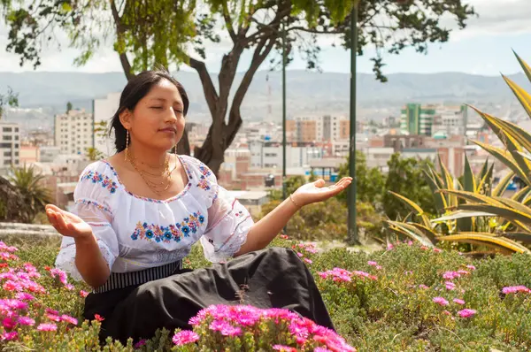 Geleneksel giyinmiş sakin bir kadın şehir arkaplanı olan renkli çiçeklerin arasında güzellikten zevk alır.
