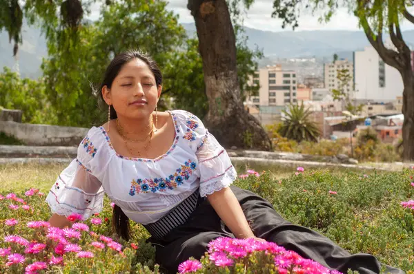 Huzurlu bir an, hareketli bir şehirde canlı çiçeklerle çevrili geleneksel giyinmiş bir kadını gösterir.