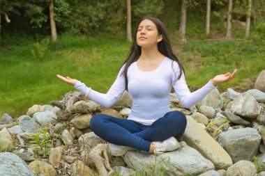 Genç bir kadın, güzel doğal bir ortamda huzurlu bir farkındalık ve meditasyon uygular.