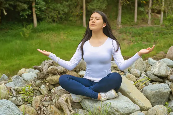 Genç bir kadın, güzel doğal bir ortamda huzurlu bir farkındalık ve meditasyon uygular.