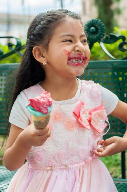 Neşeli genç bir kız renkli bir dondurma külahını tutarken, keyifle gülümserken dağınık kısımları gösteriyor.
