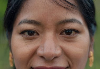 Gülümseyen bir kadının yakın plan portresi, güzel yüz hatlarını ve neşeli, sıcak ifadesini vurguluyor.