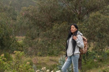 Genç bir kadın doğal ortamında şık bir sırt çantasıyla bereketli yeşillikleri keşfediyor.