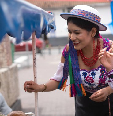 Gülümseyen genç yerli riobamba kadın geleneksel andean giysileri ve şapka giyerek Ekvador, Güney Amerika 'da bir sokak marketinde yemek satıyor.