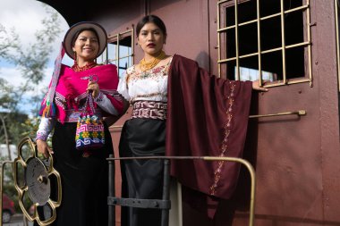 İki ekolojik model, geleneksel yerli kıyafetlerini gururla sergiliyor. Eski bir trende duruyorlar. Halklarının canlı kültürünü ve tarihini temsil ediyorlar.