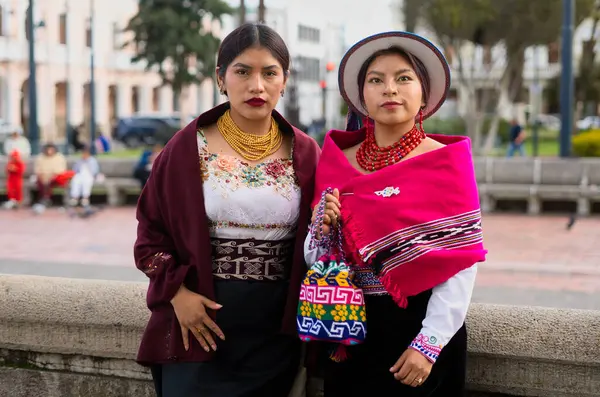 Geleneksel Andean giysileri ve mücevherleri giyen iki yerli otavalo kadın zengin kültür mirasını sergileyerek Riobamba 'daki bir parkta poz veriyorlar.