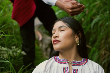 Yerli şaman, bir kadının kafasına su dökerek dingin ve ruhani bir atmosfer yaratıyor.
