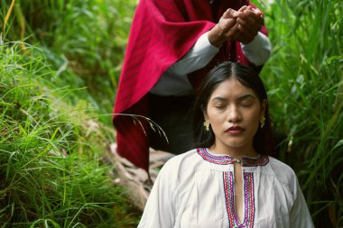 Yerli şaman ruhani ayin sırasında genç kadının kafasına su dökerek yemyeşil bitki örtüsüyle çevrili, kültürel turizmi destekliyor ve antik gelenekleri keşfediyor.