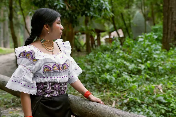 Panama 'da tipik bir ngbe evinin yakınındaki bir ormanda geleneksel nakışlı giysiler ve kolye giyen Ngbebugl kadını, kültürel mirasını gururla gösteriyor.