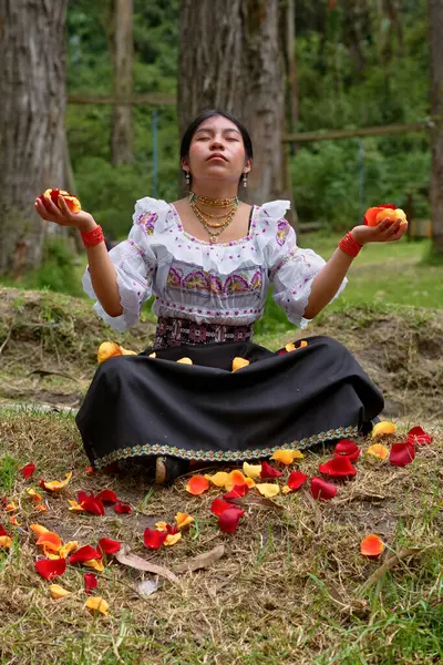 Yerli bir kadın orman açıklığında meditasyon yapıyor. Etrafı renkli gül yapraklarıyla çevrili ve elinde biraz da dinginlik ve maneviyat fışkırıyor.