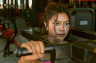 Genç kadın vücut geliştirici spor salonunda omuzlarında ağır ağırlıklarla güç antrenmanı yapıyor. Kararlılığını gösteriyor ve fitness hedeflerine odaklanıyor.