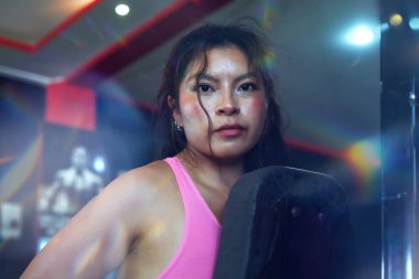 Modern spor salonundaki yoğun antrenman sırasında ağırlık kaldıran güçlü kadın vücut geliştirici, fitness hedeflerine kendini adamış ve gücünü gösteriyor.