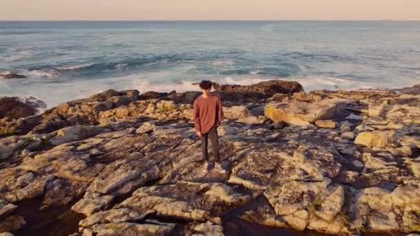 荒波が吹く岩の崖の上に立つ若い男Arteixo Coruna Galicia スペイン プルバックショット — ストック動画