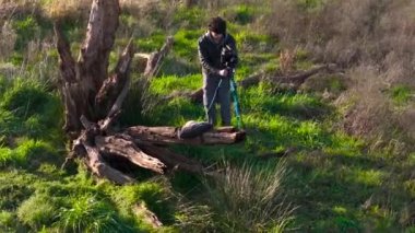 Kameralı açık hava fotoğrafçısı ve tarladaki ölü ağaç odununun yanında tripod. İHA atışı