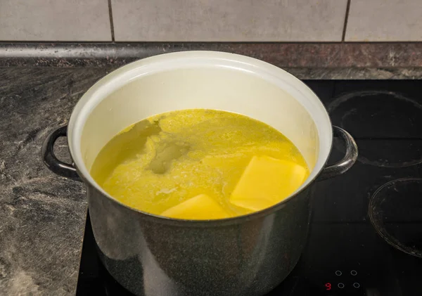 Cooking of marijuana butter in hot water on electric black cooker in kitchen