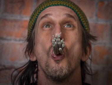 Yeşil şapkalı kıllı bir adam ve eski tuğla duvarın yanında on esrarkeş.