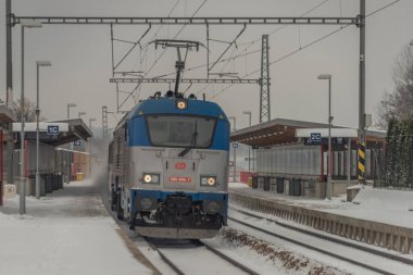 Veseli nad Luznici yakınlarındaki hızlı yolcu treni karlı platformlar ve karanlık bulutlu gökyüzü ile durdu