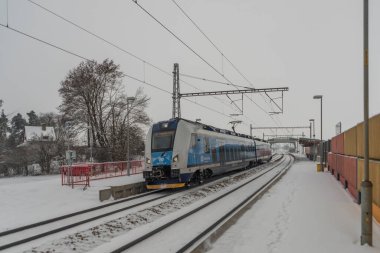 Veseli nad Luznici yakınlarındaki hızlı yolcu treni karlı platformlar ve karanlık bulutlu gökyüzü ile durdu
