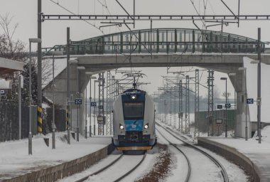 Veseli nad Luznici yakınlarındaki hızlı yolcu treni karlı platformlar ve karanlık bulutlu gökyüzü ile durdu