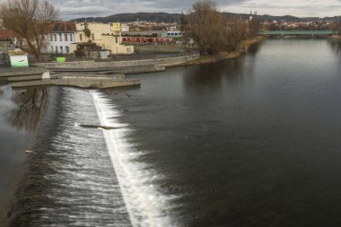 River Otava and weir with pedestrian bridge near Pisek town in south Bohemia in winter evening