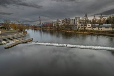 River Otava and weir with pedestrian bridge near Pisek town in south Bohemia in winter evening
