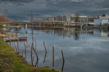 River Otava and weir with pedestrian bridge near Pisek town in south Bohemia in winter evening