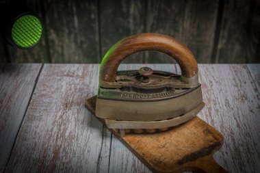 Eski ahşap masa üzerinde eski metal ütü ve kirli kesim tahtası.