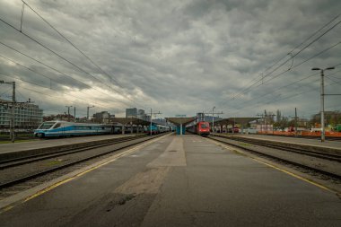 Yolcu trenleri bulutlu bahar mevsiminde başkenti Ljubljana 'da karanlık bir günde istasyonda.