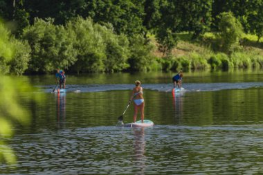 Sıcak bir günde Vltava nehrinde mavi mayolu bir kadınla kürek çek.