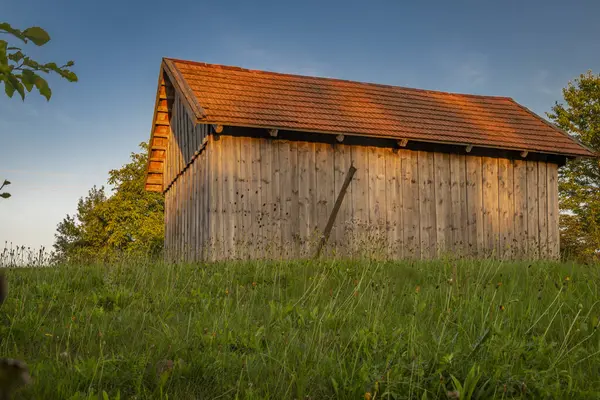 夏の夕方にクリノース山脈の日没色と青空の古い木製の納屋 — ストック写真