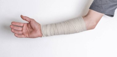 Kırmızı avuç içi ve beyaz duvar arkaplanı olan bandajlı erkek kol.